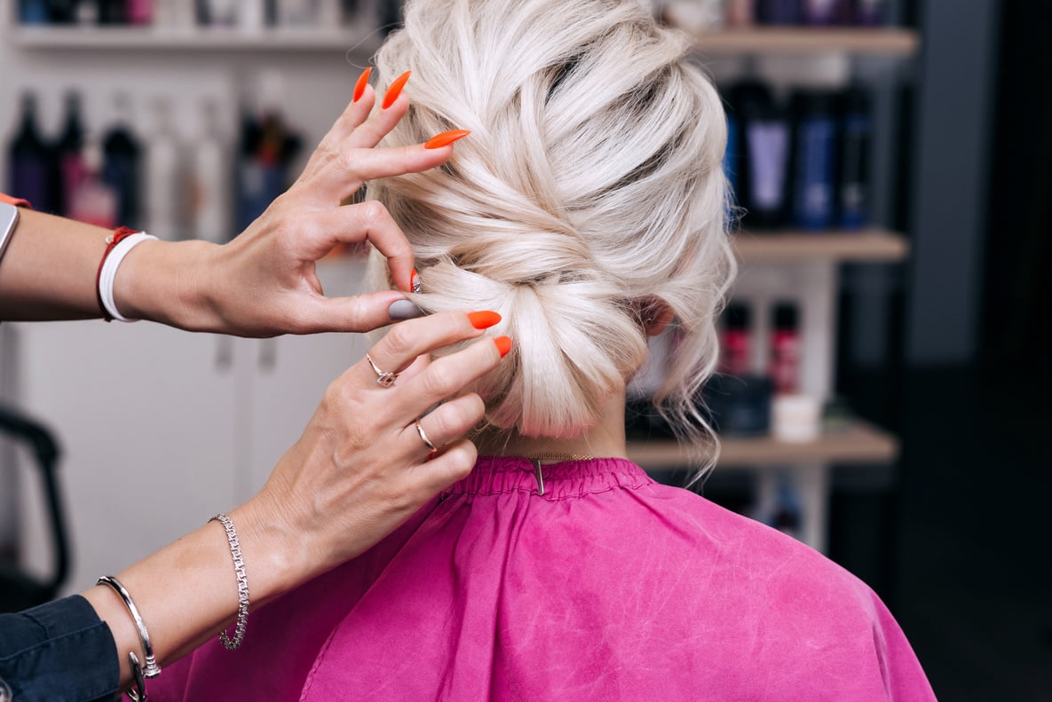 Hands of a Professional Hairstylist Make a Hairstyle for a Blonde Girl with Long Hair